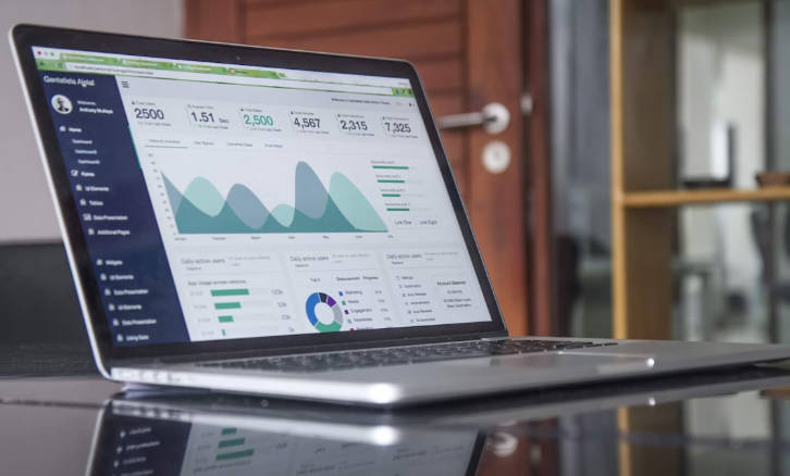 Um computador portátil ligado sobre uma mesa de vidro. A Turned-on Laptop Computer on Glass-top Table