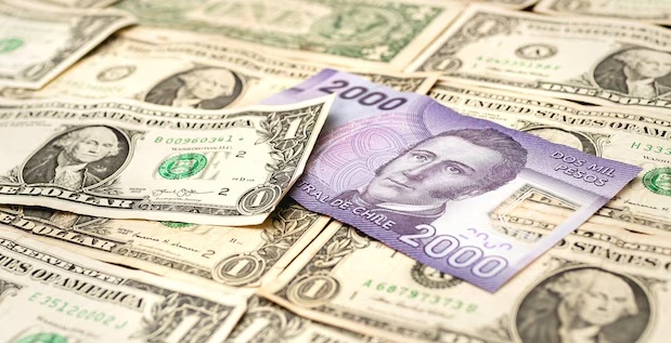 Billetes de dólares junto a billete de pesos chilenos