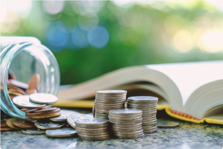 A Jar with Coins Placed Beside It