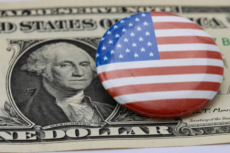A button with the American flag on it sitting on top of a hundred dollar bill A button with the American flag on it sitting on top of a hundred dollar bill